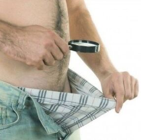 um homem olha para baixo nas calças e quer aumentar o pênis com gel